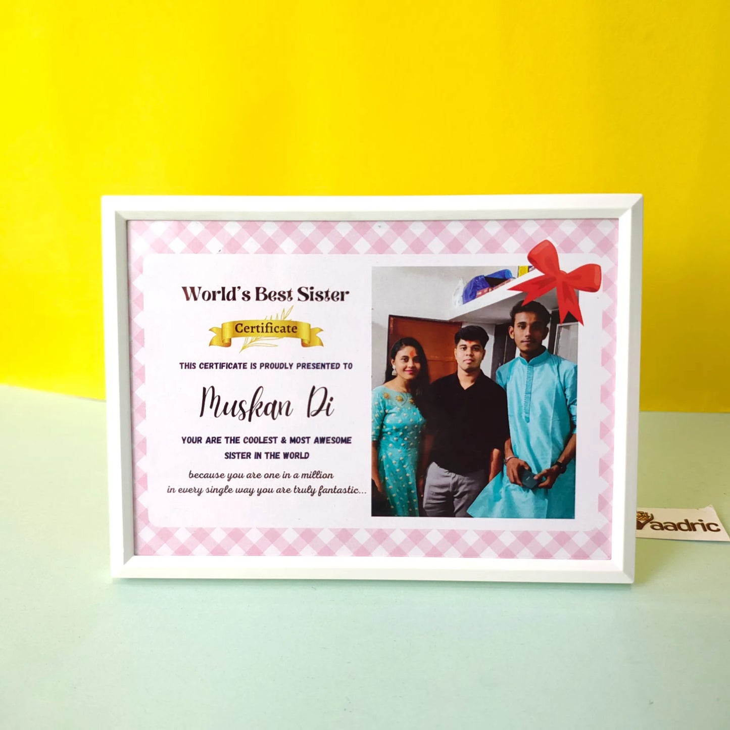 Framed certificate titled 'World's Best Sister' with a photo of three people on a yellow and green gradient background.