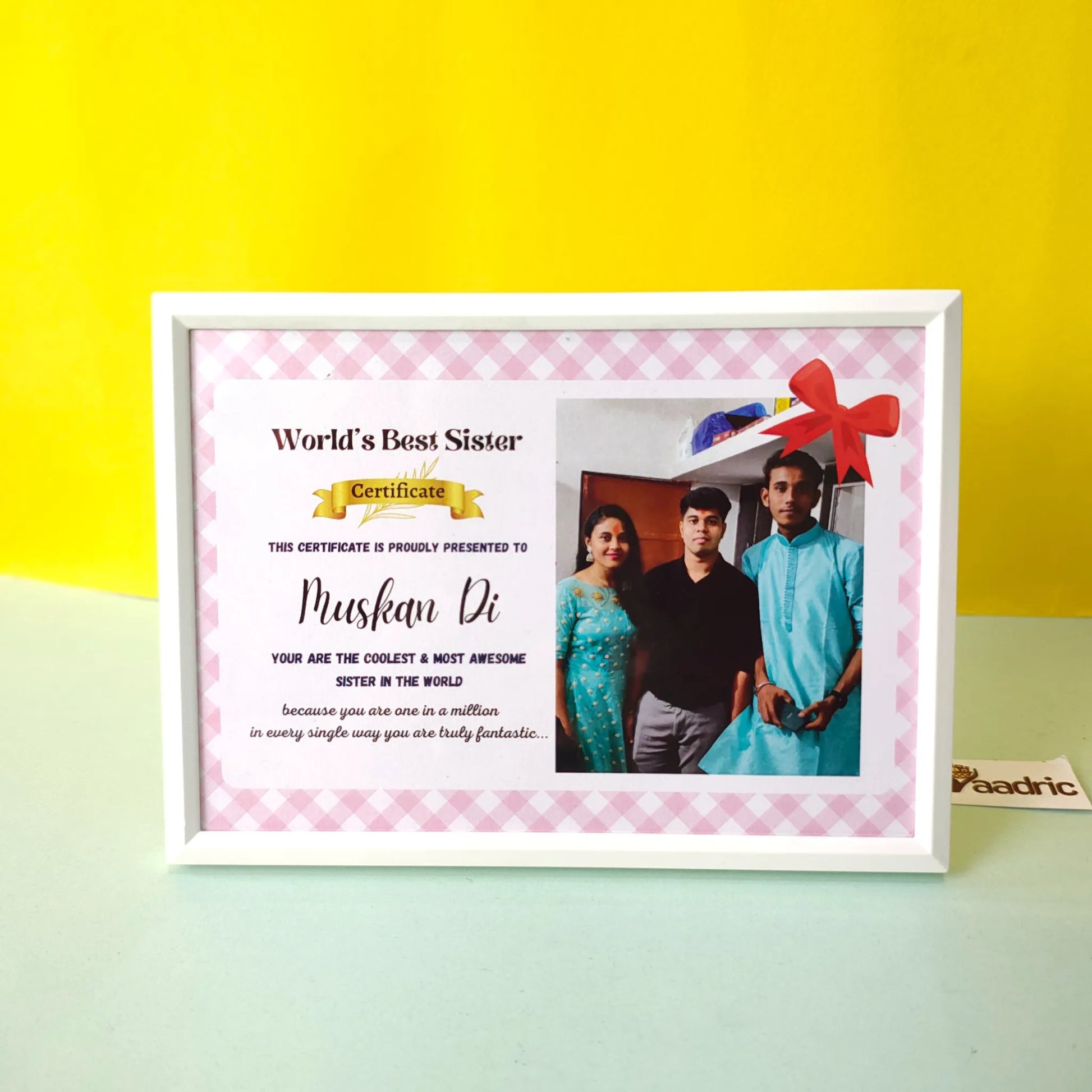 Framed certificate titled 'World's Best Sister' with a photo of three people on a yellow and green gradient background.