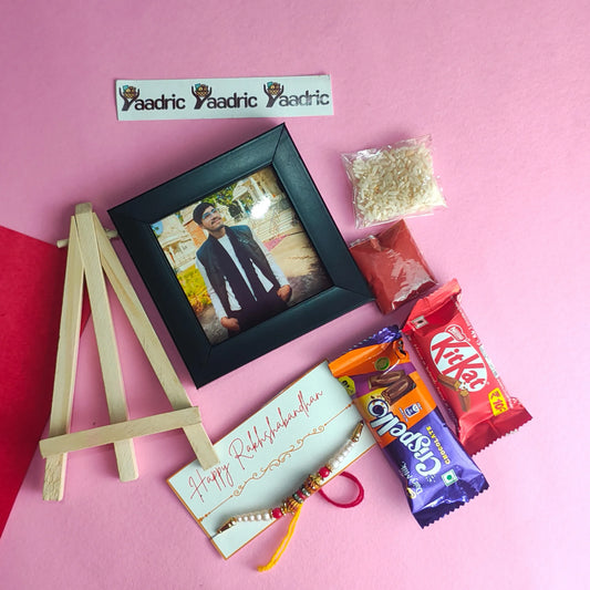 Small photo frame with a man's portrait, a small wooden easel, and candy bars on a pink background.