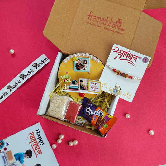 Gift box with Rakhi, cards, and snacks on a red background